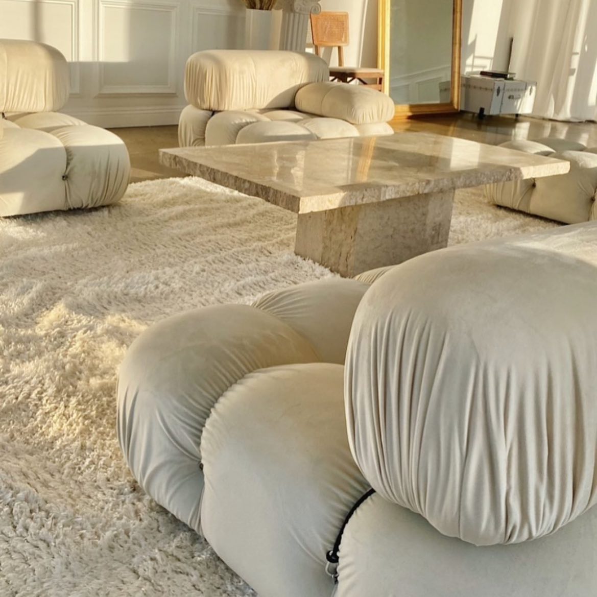 Three white sofas with a white glass table in the middle